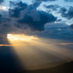 he bright rays of the sun are shining from saturated clouds to mountain. CREDIT: PhilipYb Studio/Shutterstock.com.